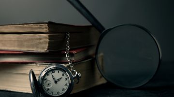 Livros, relógio e lupa em uma mesa
