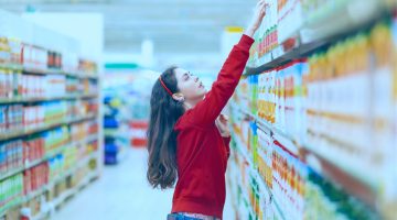Cliente em um corredor de sucos de frutas em supermercados analisando o NCM do produto