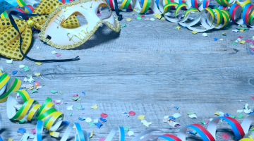 itens típicos de um carnaval tributário espalhados em uma mesa de madeira clara