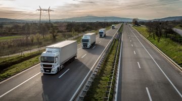 caminhões andando em uma estrada, fazendo menção à relação entre ICMS e logística