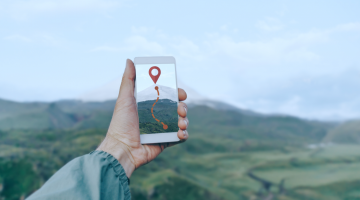 mão estendida ao centro da imagem com localização na tela, em um cenário de campo, fazendo menção ao novo conceito de praça