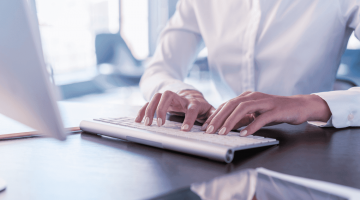 mãos femininas digitando em um teclado, fazendo menção ao processo de consulta