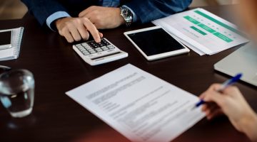 Pessoas mexendo em papel e calculadora, em referência a crédito tributário