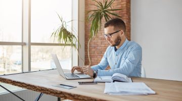 homem de camisa social trabalhando no notebook, fazendo menção à IN referente aos royalties