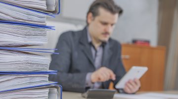 pessoa escrevendo em um papel, em referência retificar-a-Declaração do Imposto de Renda.