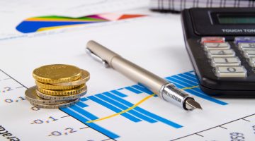 isencao-fiscal: mesa com moedas, caneta e papel com gráficos